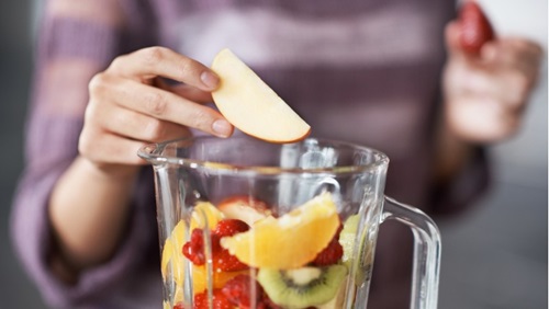 vrouw doet fruit in blender